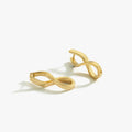 A pair of 18K gold vermeil spiral earrings displayed on a white background. The earrings feature a twisted, infinity-like design, emphasizing their contemporary style.