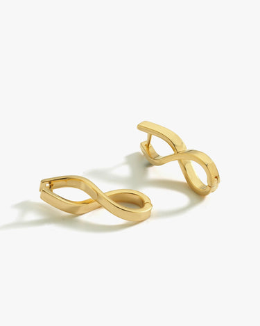 A pair of 18K gold vermeil spiral earrings displayed on a white background. The earrings feature a twisted, infinity-like design, emphasizing their contemporary style.