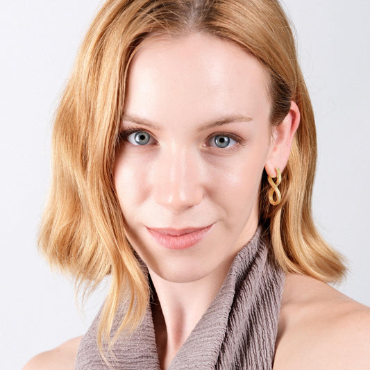 A front-facing portrait of a light-skinned woman with blonde hair, wearing 18K gold vermeil spiral earrings.