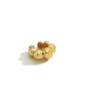 Isolated gold ear cuff with spherical beads on a white background.