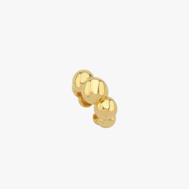 Close-up view of a gold ear cuff with three spherical beads on a white background.