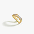 A gold ear cuff with baguette-cut clear stones, positioned on a white background. The cuff has a gently curved design, creating an elegant and minimalistic look.