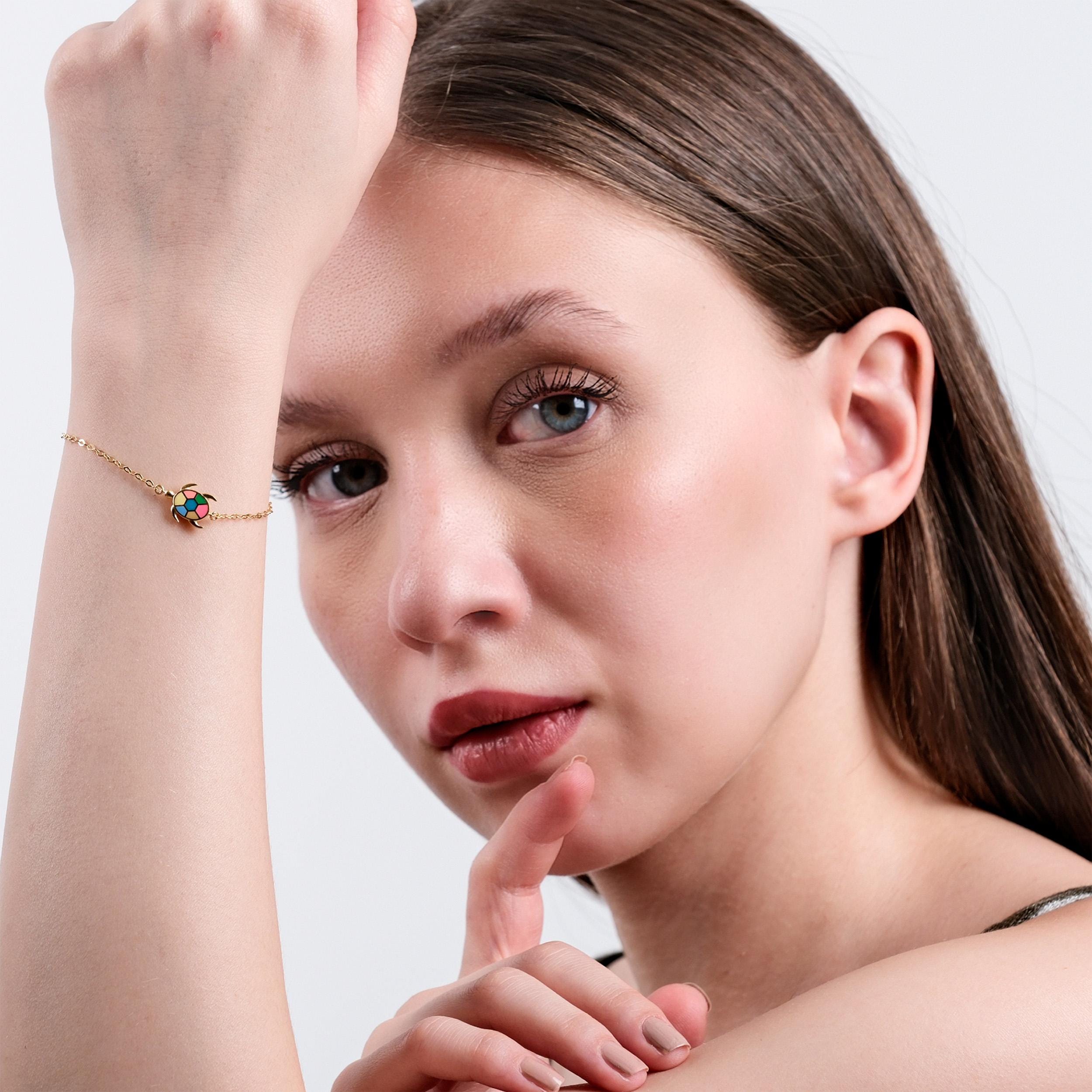 Woman posing with colorful turtle bracelet, displaying elegant jewelry fashion and natural beauty.