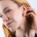 A woman with blonde hair touching her 18K gold vermeil tear drop earring.