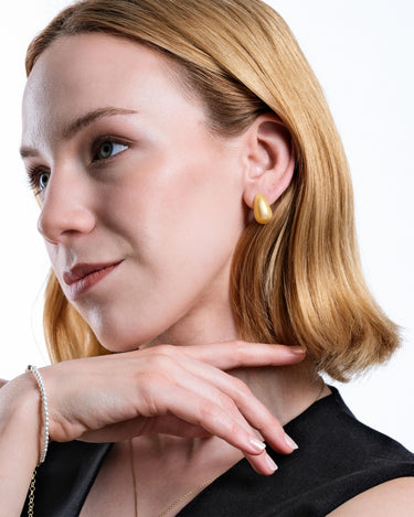 A side profile of a woman wearing 18K gold vermeil tear drop earrings.