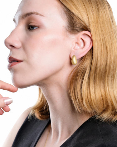 Close-up of a pair of 18K gold vermeil tear drop earrings, with one earring facing forward and the other showing the back post.