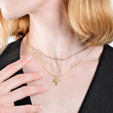 Close-up of a woman with fair skin and blonde hair, wearing two gold necklaces, one of which is an 18K gold vermeil mushroom pendant.