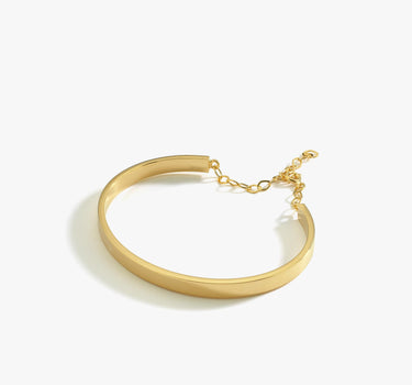 A side view of an 18K gold vermeil cuff bracelet with a chain extender, displayed flat on a white background.