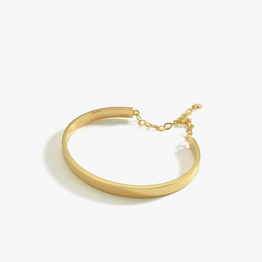 A side view of an 18K gold vermeil cuff bracelet with a chain extender, displayed flat on a white background.