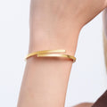 A close-up of a wrist wearing a minimalist 18K gold vermeil hinged bangle bracelet with a sleek, modern design.