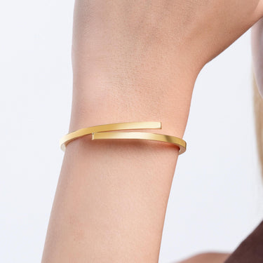 A close-up of a wrist wearing a minimalist 18K gold vermeil hinged bangle bracelet with a sleek, modern design.