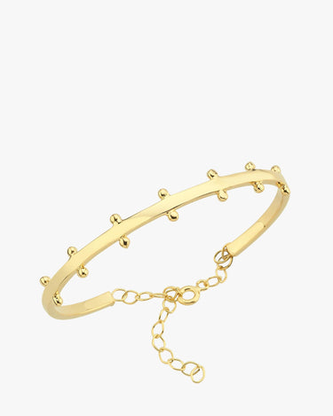 A close-up product image of the 18K gold vermeil station cuff bracelet, featuring small gold rounded stations along its curved band and a delicate chain clasp for adjustable sizing.