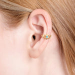 Close-up of a woman's ear wearing a gold vermeil ear cuff in the shape of an eye with a turquoise stone at the center.