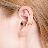 Close-up of a woman's ear wearing a gold vermeil ear cuff in the shape of an eye with a turquoise stone at the center.