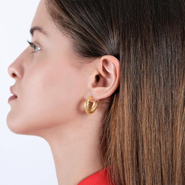 Side profile of a woman wearing 18K gold vermeil chunky hoop earrings, her straight hair parted and resting on her shoulder.