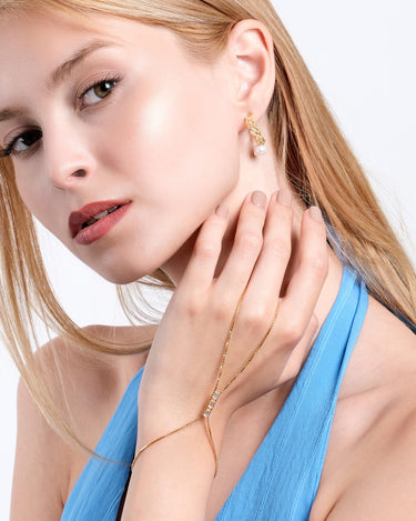 Woman wearing an 18K gold vermeil box chain ring bracelet and matching gold earring.