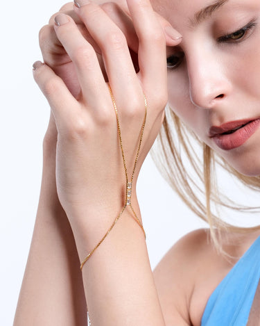 Woman gently holding her hand, wearing an 18K gold vermeil box chain ring bracelet.