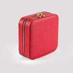 A compact, red travel jewelry box with gold zipper details, perfect for safely storing a First Holy Communion Bracelet.