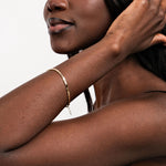 A model with long, flowing hair wearing a 14K gold mirror chain bracelet, adding a touch of sophistication.
