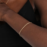 A close-up of a delicate 14K gold bracelet with a subtle shine, complementing the skin.