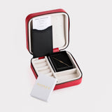The interior of a red jewelry box, showcasing a neatly placed First Holy Communion Bracelet along with a certificate.