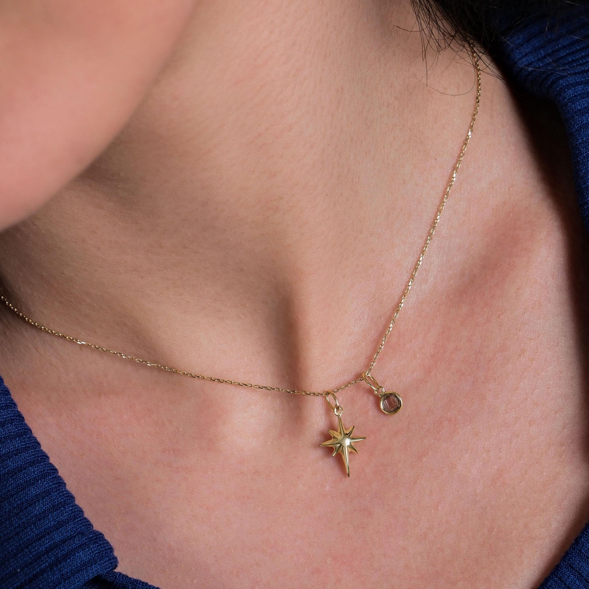 A close-up of a woman&#39;s neck showcasing a delicate 14K Solid Gold North Star Pendant hanging from a fine gold chain.