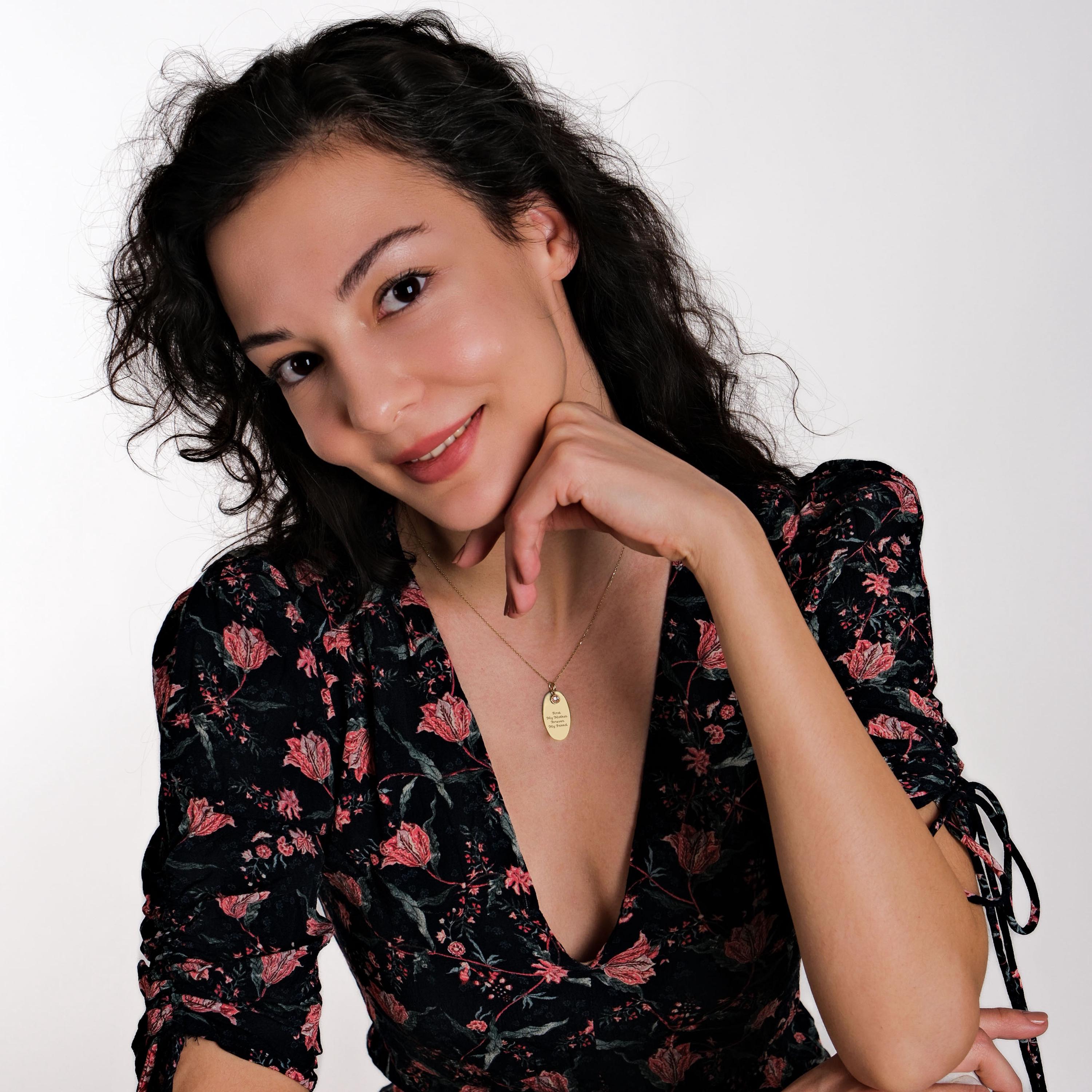 A woman wearing a floral dress, smiling while wearing the personalized gold necklace, emphasizing its elegant and sentimental design.