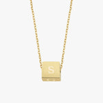 A floating cube pendant on a fine gold chain, engraved with the letter "S", photographed against a white background.
