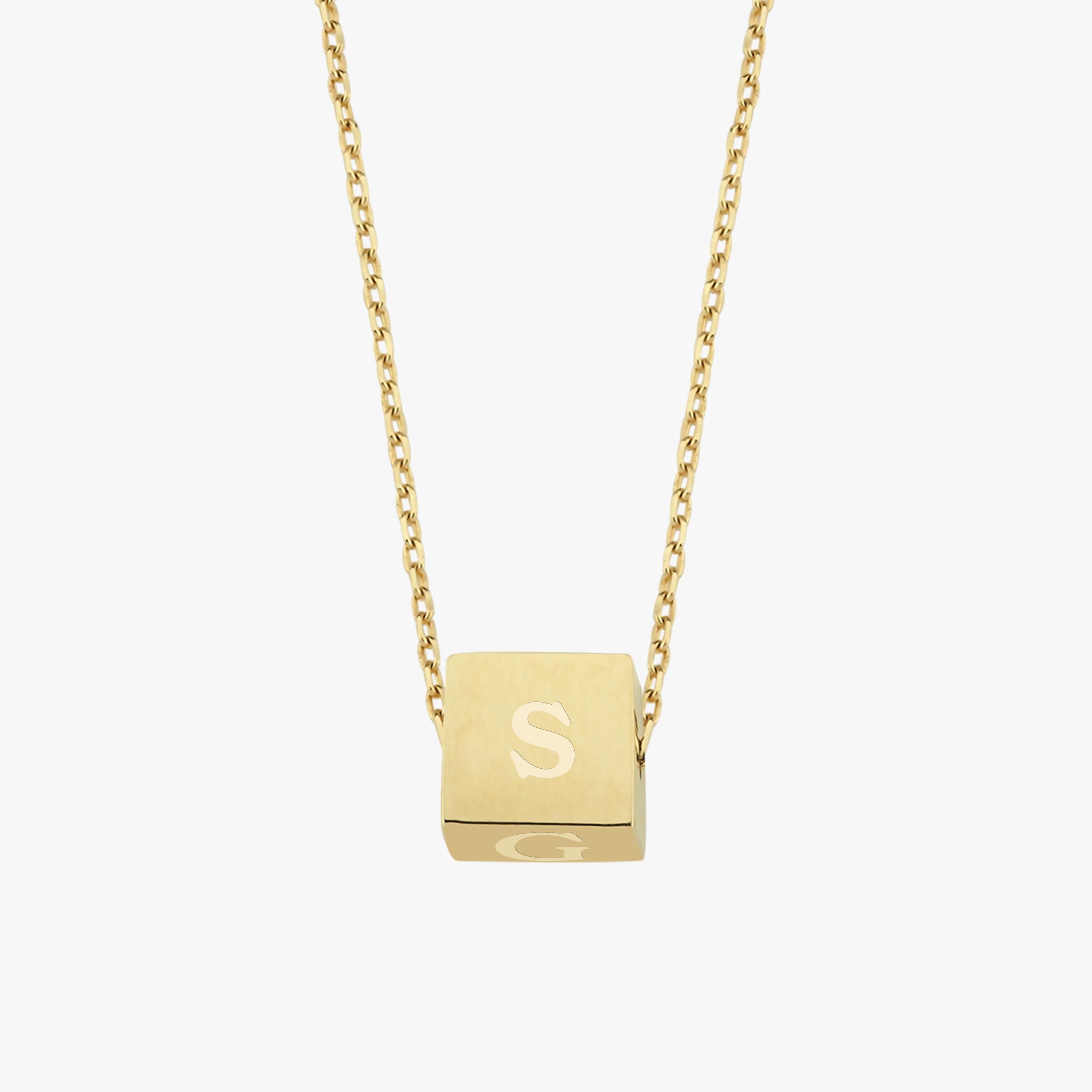 A floating cube pendant on a fine gold chain, engraved with the letter "S", photographed against a white background.