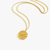 A model wearing the 18K gold vermeil compass necklace, styled with a striped blue and white top.