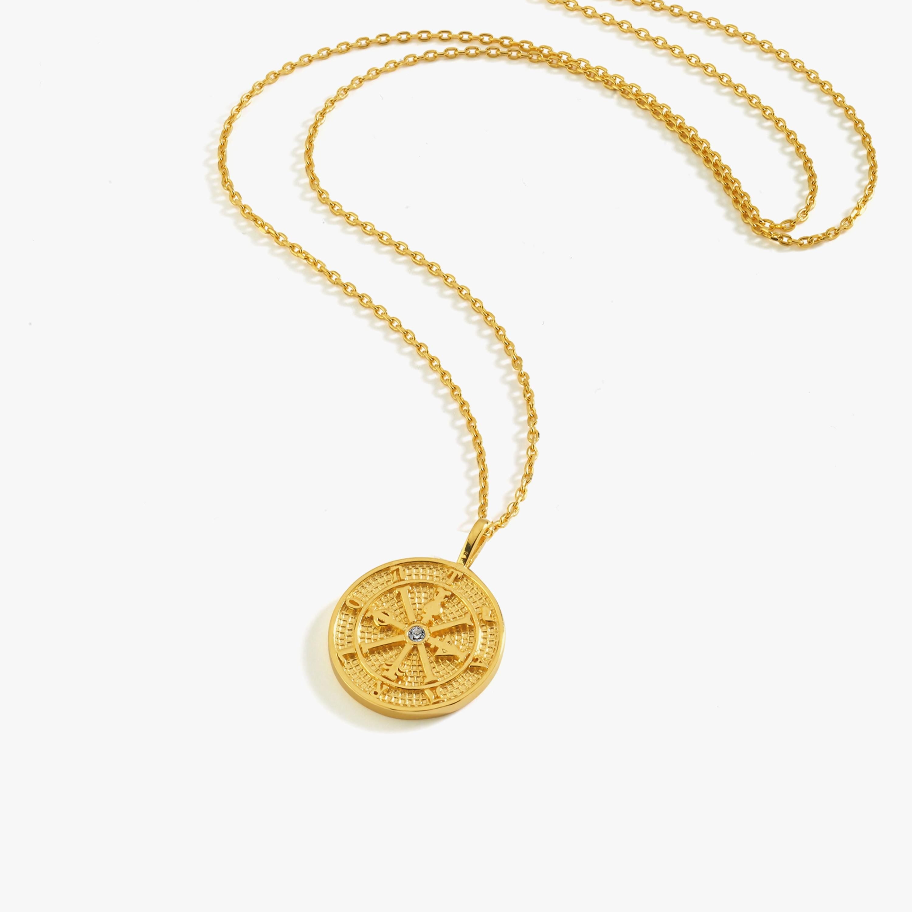 A model wearing the 18K gold vermeil compass necklace, styled with a striped blue and white top.