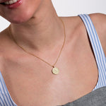 The compass pendant necklace displayed against a white background, showcasing intricate detailing and a tiny center gemstone.