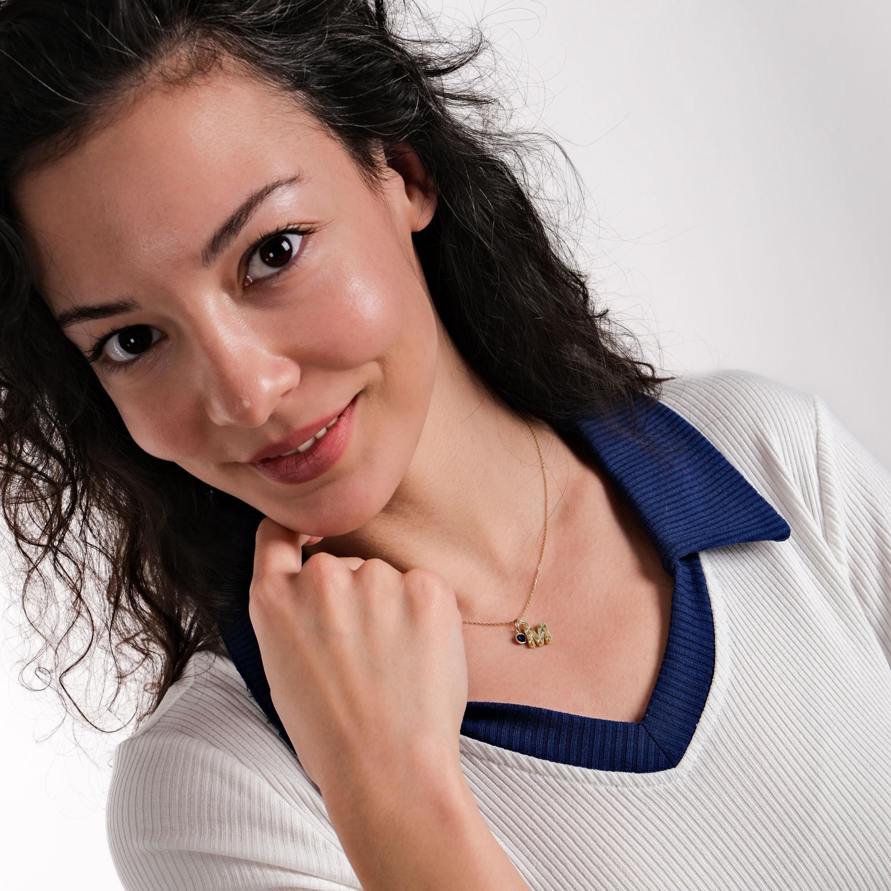 A woman smiling while wearing a 14K Solid Gold Initial Necklace with Birthstone, adding a personalized and elegant touch to her outfit.