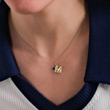 A close-up of a woman’s neckline adorned with a 14K Solid Gold Initial Necklace with Birthstone, perfectly complementing her navy and white outfit.