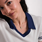 A side-angle view of a woman wearing the 14K Solid Gold Initial Necklace with Birthstone, capturing the subtle sparkle of the gold pendant and gemstone charm.