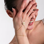 A close-up of an elegant gold hand chain with a dainty daisy pendant, draping beautifully over the wrist.