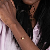 14K Solid Gold Cube Initial Bracelet – A sleek gold bracelet elegantly worn on the model’s wrist.