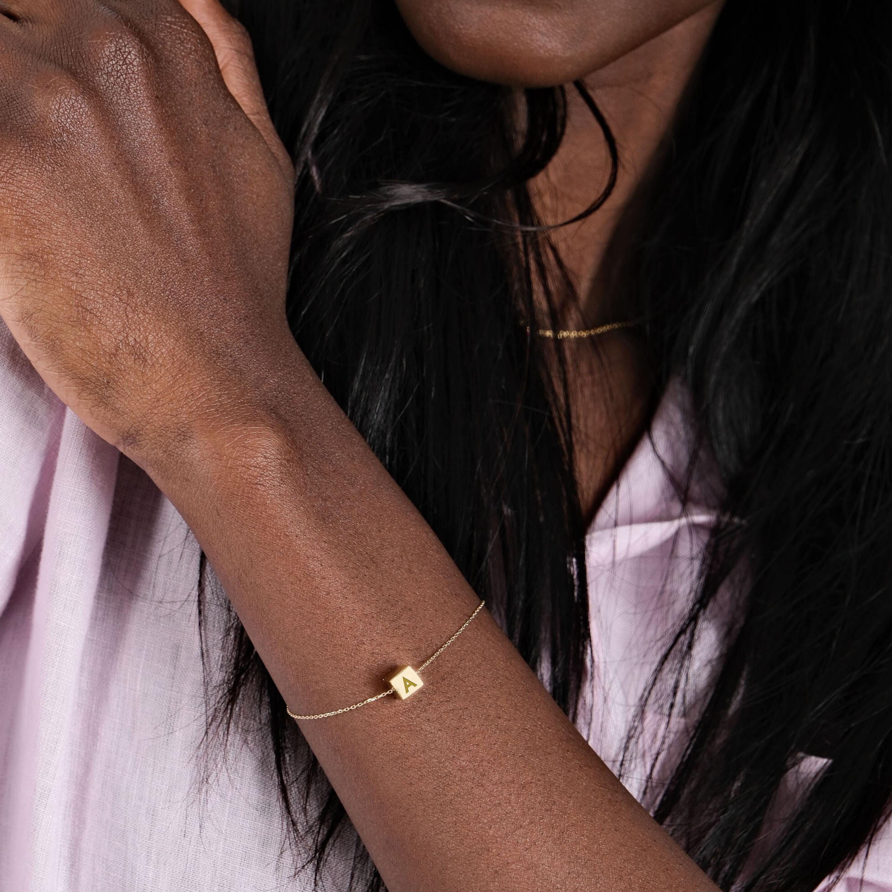 14K Solid Gold Cube Initial Bracelet – A sleek gold bracelet elegantly worn on the model’s wrist.