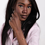 14K Solid Gold Cube Initial Bracelet – The model stylishly showcasing the personalized gold bracelet with a pink blouse.