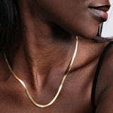 Side view of a woman wearing an 18K gold vermeil personalized herringbone necklace with subtle engraving near the collarbone.