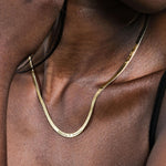 Close-up of a woman wearing an 18K gold vermeil personalized herringbone necklace engraved with “Emily ♥ James.”