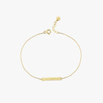 Flat-lay of a 14K solid gold engraved bar bracelet with adjustable clasp and Roman numeral engraving.