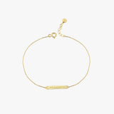 Flat-lay of a 14K solid gold engraved bar bracelet with adjustable clasp and Roman numeral engraving.