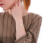 Side view of a woman wearing a 14K solid gold birthflower bracelet with a floral engraving and “Rachel” inscription.