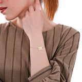 Side view of a woman wearing a 14K solid gold birthflower bracelet with a floral engraving and “Rachel” inscription.