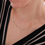 Close-up of a woman wearing a 14K solid gold mama necklace, styled with a striped deep V-neck top.