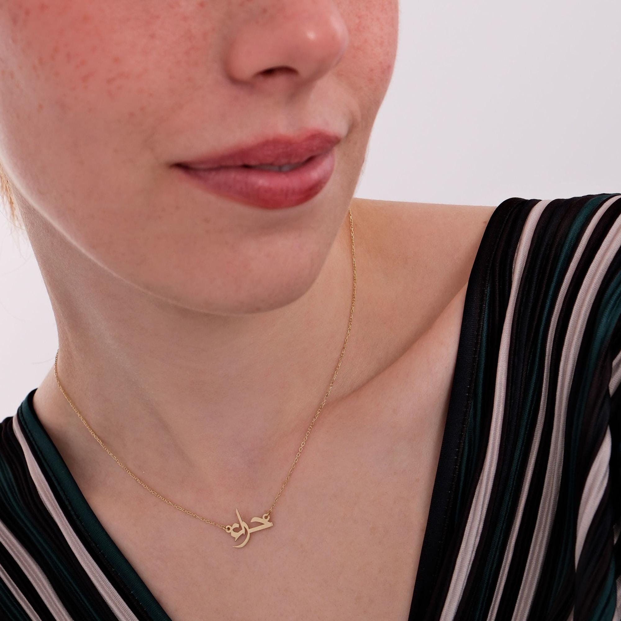 Close-up side view of a woman’s lower face and neck, highlighting a 14K solid gold Arabic name necklace with a graceful, minimalistic chain and a personalized script pendant.