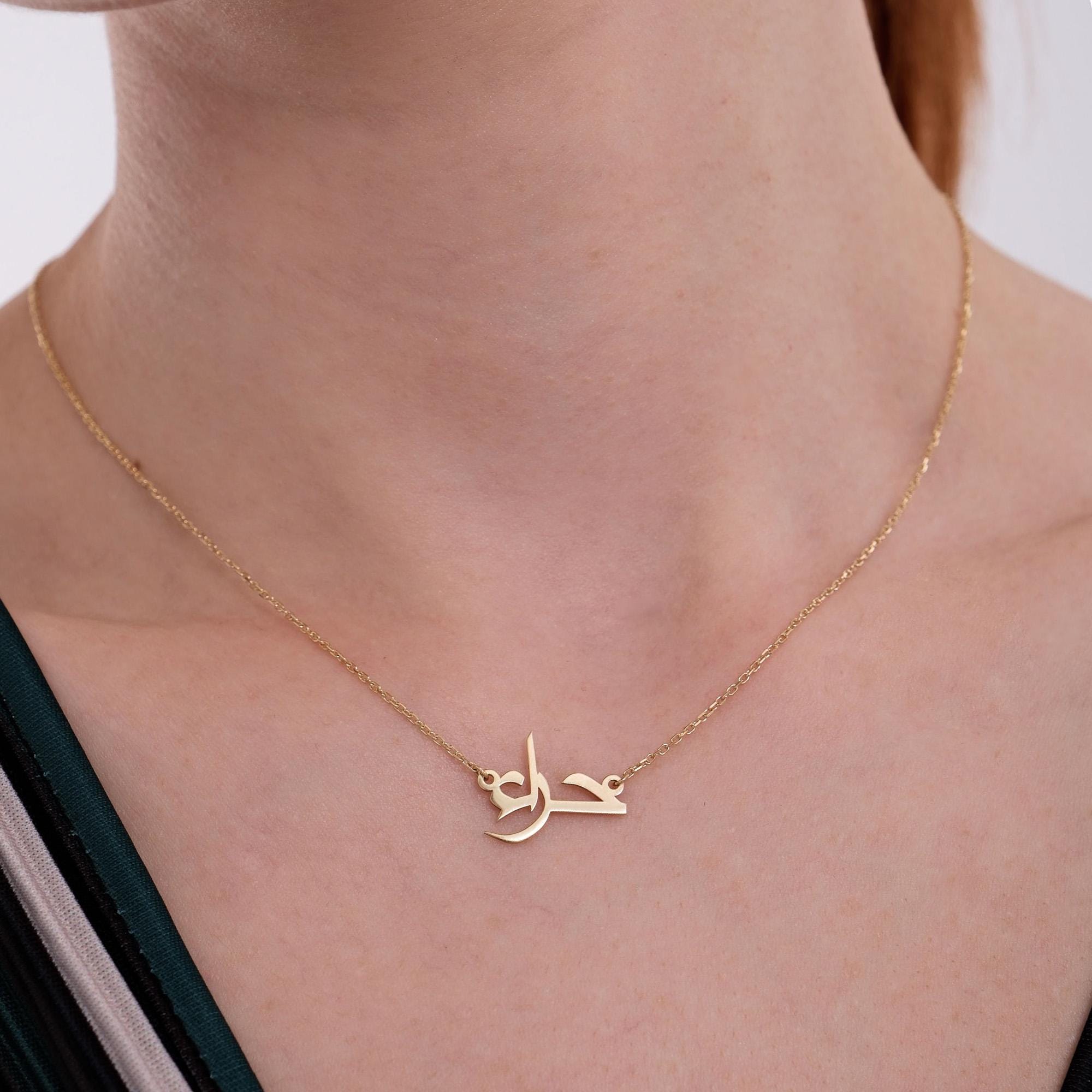 Close-up of a woman's neck wearing a delicate 14K solid gold Arabic name necklace with a fine chain, showcasing the intricate Arabic calligraphy in the pendant.