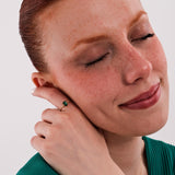 With closed eyes and a serene smile, the model gently touches her face, highlighting the 14K Solid Gold Emerald Cut Ring on her hand.