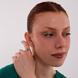 The model looks to the side while resting her hand near her ear, wearing a 14K Solid Gold Emerald Cut Ring that adds a bold touch to her look.
